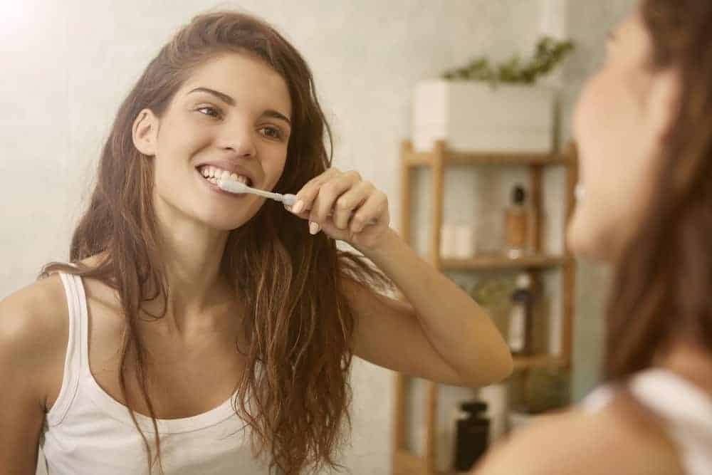 一個女人一邊刷牙一邊照鏡子