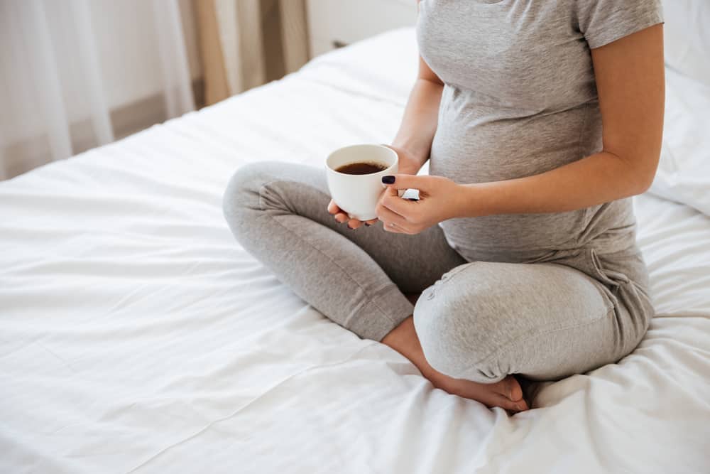 孕婦坐在床上喝咖啡